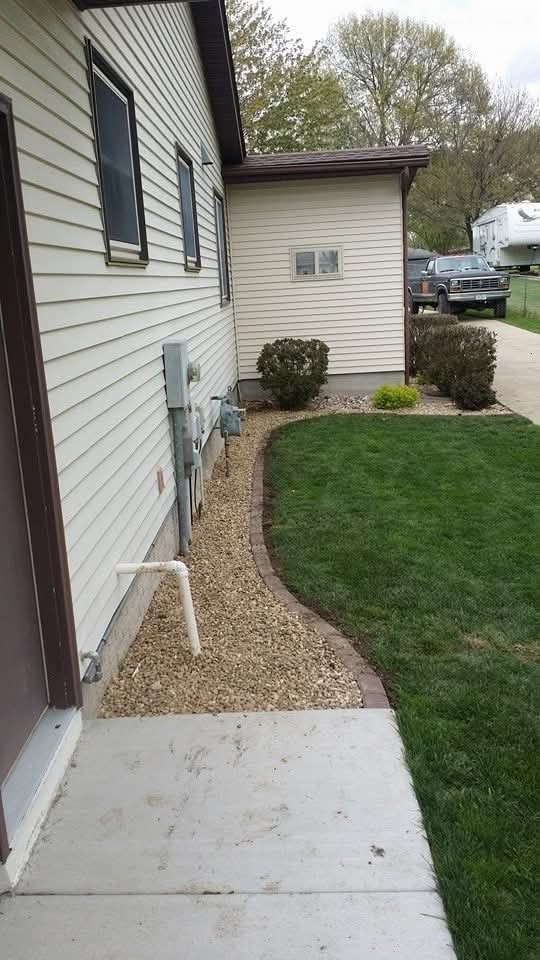 Side yard gravel bed with brick edging — shrubs and utility area