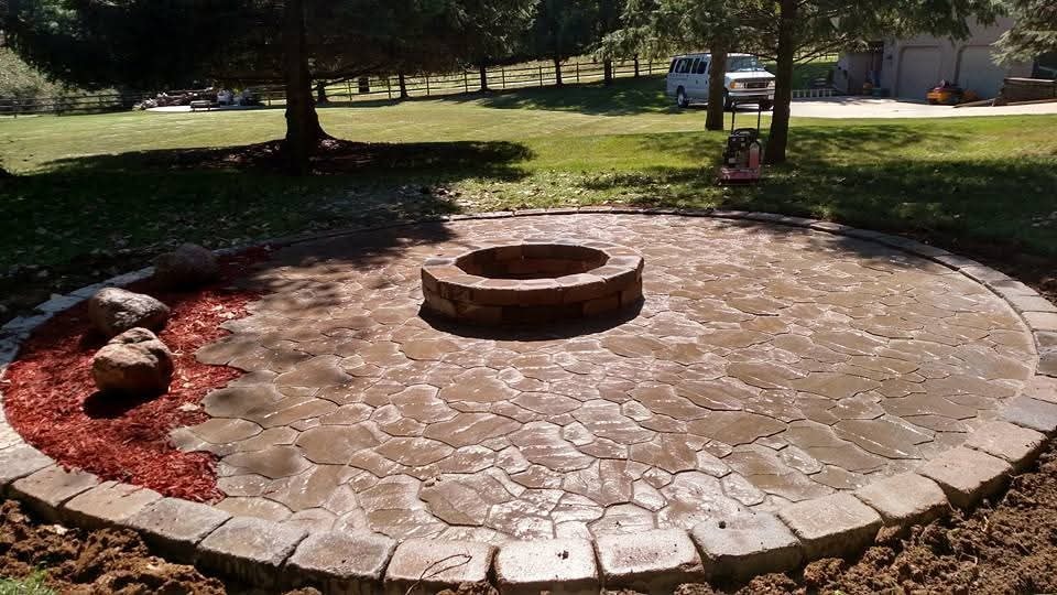 Circular paver patio with stone fire pit — flagstone pattern, red mulch border
