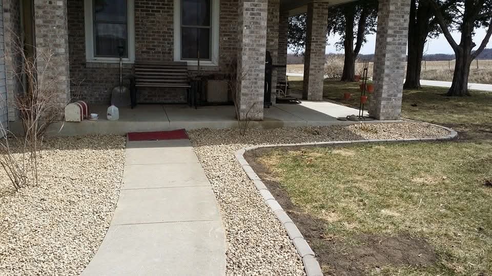 Concrete walkway with gravel beds and brick edging — rural brick home front entry