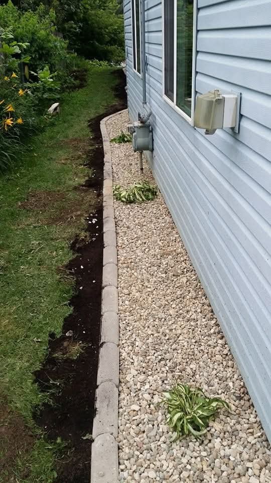 Gravel foundation bed with block edging — side of blue siding home with hostas