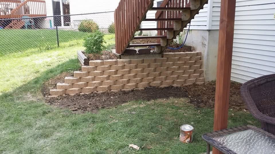 Block retaining wall under deck stairs — backyard planter bed, chain-link fence