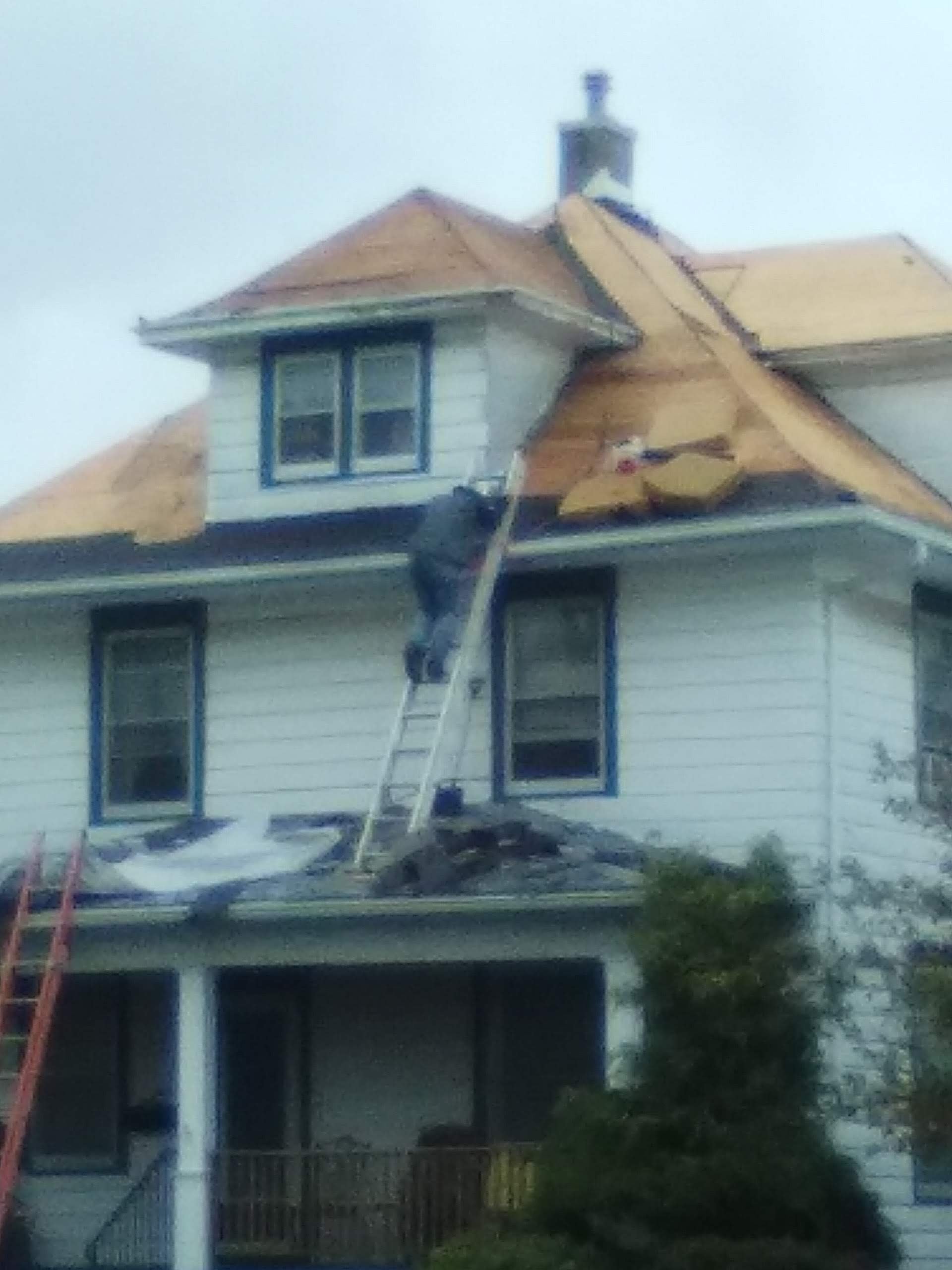 Residential roof tear-off in progress — two-story home