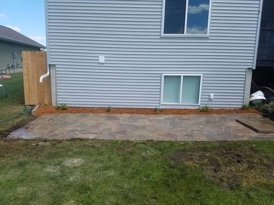 Flagstone patio installation — backyard slab with mulch border