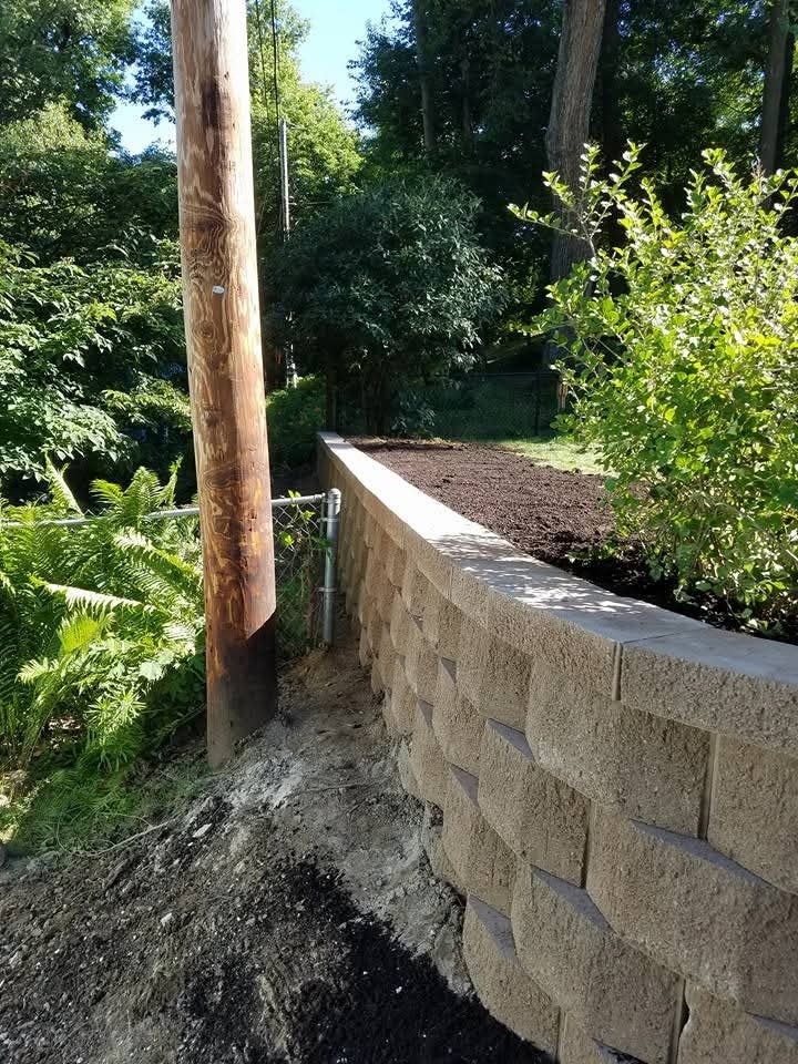 Tall block retaining wall — freshly backfilled garden bed