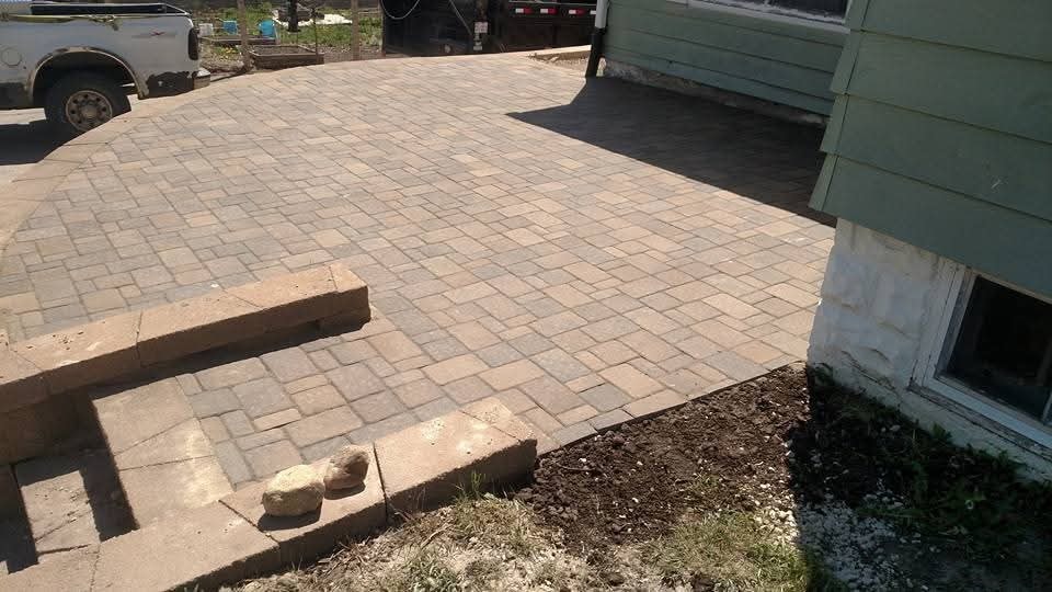 Completed paver patio — large brick-pattern surface with step access