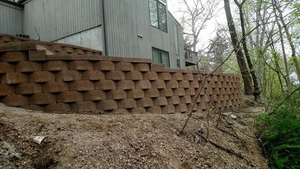 Massive block retaining wall — wooded hillside, full run view