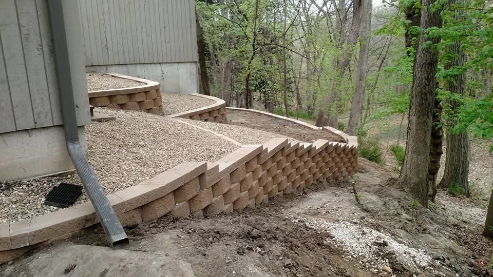 Multi-tier curved retaining walls with gravel beds — wooded lot