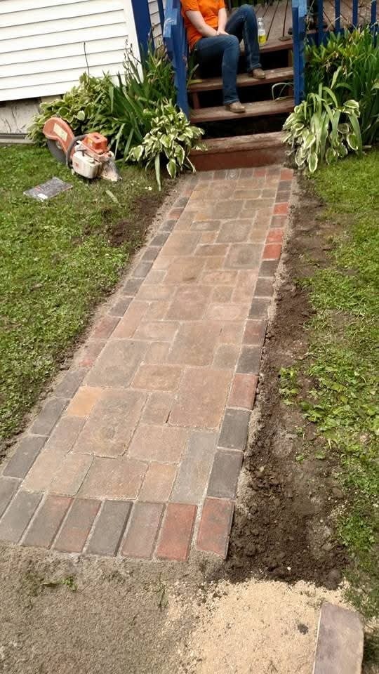 Brick paver walkway installation — front entry path with saw and crew