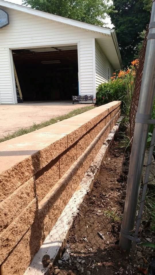 Block retaining wall along garage driveway — fresh install with day lilies