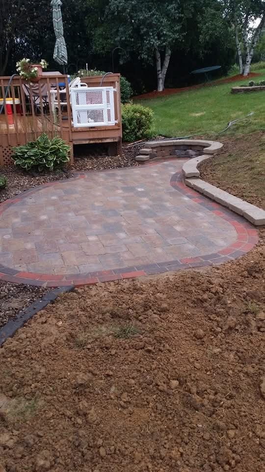 Completed brick paver patio with curved border — backyard with deck and landscaping